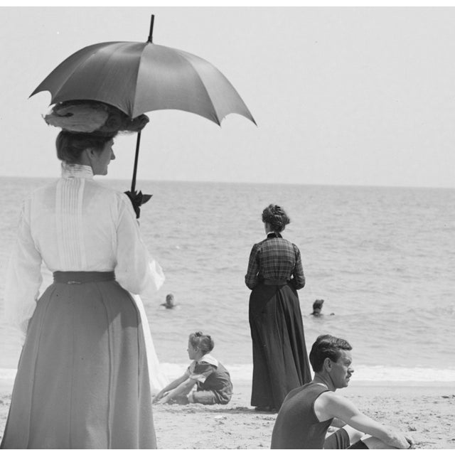 This vintage beach photo shows an assortment of early 20th century beach goers in various forms of dress in Palm Beach,...