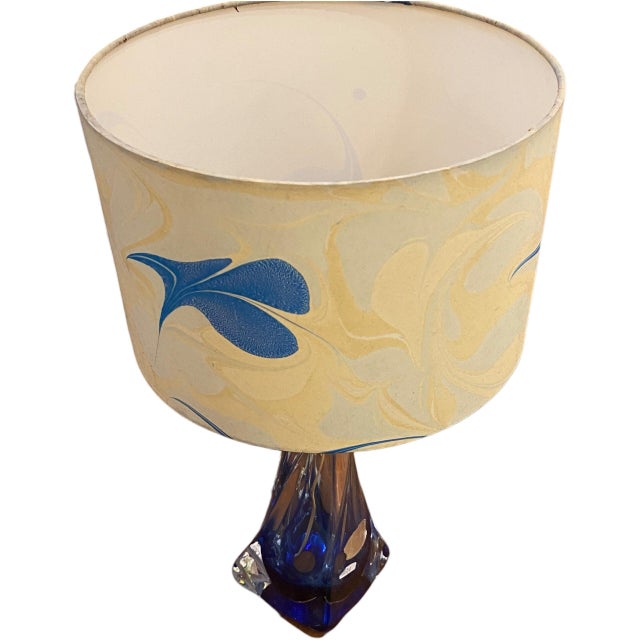 The lamp body begins in a deep blue at its base and gradually transforms into lighter tones as it twists towards the neck....