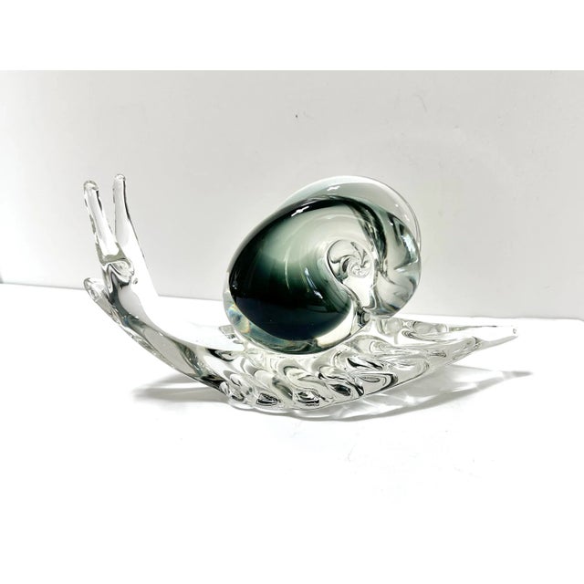 A whimsical Murano-style handblown glass snail sculpture featuring elegant two-tone coloration and smooth organic curves....