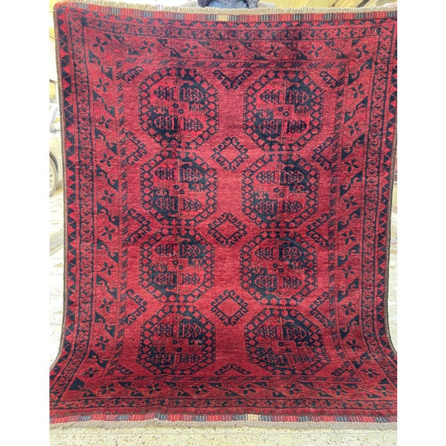 This striking Turkmen rug presents bold elongated octagonal medallions arranged in offset rows across a deeply saturated...
