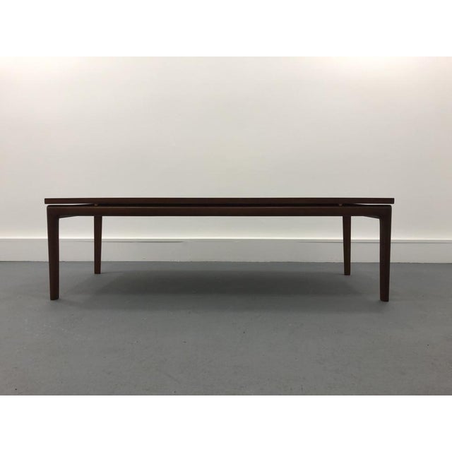 This vintage coffe table is made of teak veneered solid wood and features a floating effect top. It was designed by Ole...