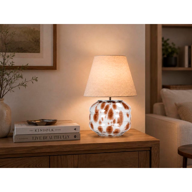 Crafted with high visual clarity, this modern table lamp features a sleek silhouette with a hand-blown glass base paired...