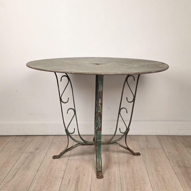 An Art Deco French wrought iron garden table with weathered green finish.