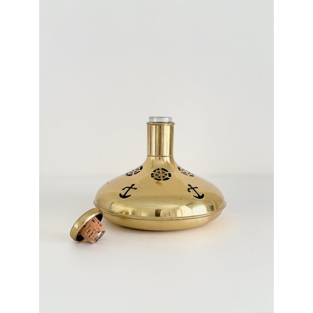 A brass-encased glass Ship’s Decanter with nautical cutouts, made in Sweden circa 1950s. Marked “Made in Sweden” on the...