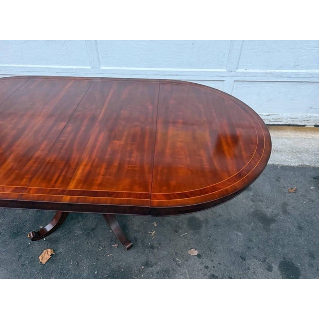 Vintage Regency Style Pedestal inlaid Mahogany Round Dining Table With 2 Leaves. The base is carved Features pedestal on...