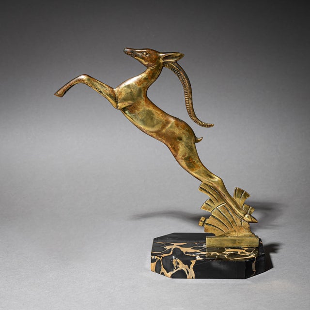 Pair of opposing bookends in brass with stylized leaping gazelles, mounted on dark marble plinths.