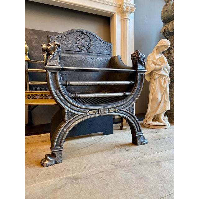 An elegant and good quality English 19th century regency style fire grate in polished cast iron. The lion heads finials...