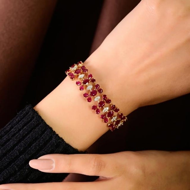 This statement bracelet features oval and pear cut ruby totaling 20.96 carats, set in 14k yellow gold. rubies measuring...