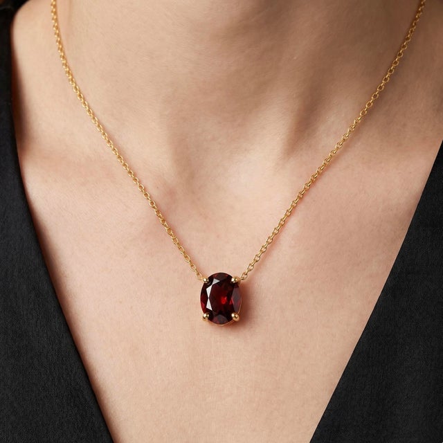 Elevate your jewelry collection with this elegant Garnet Solitaire Necklace, featuring a richly colored oval-cut garnet...