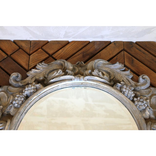 A stunning example of Italian craftsmanship, this large oval mirror is framed by an intricately hand-carved wooden...