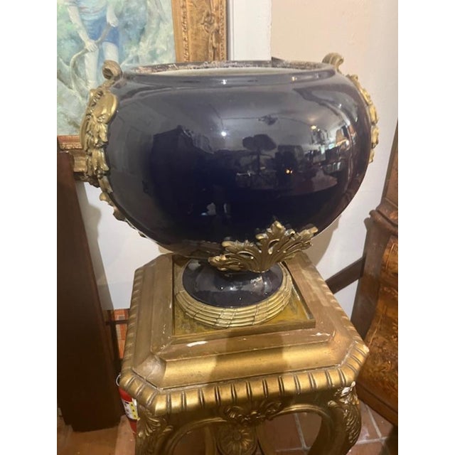 This antique vase on stand is a stunning piece of artistry. The blue ceramic material is beautifully complemented by the...