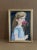 This expressive watercolor portrait of a young girl holding a pink carnation conveys innocence and introspection. Framed...