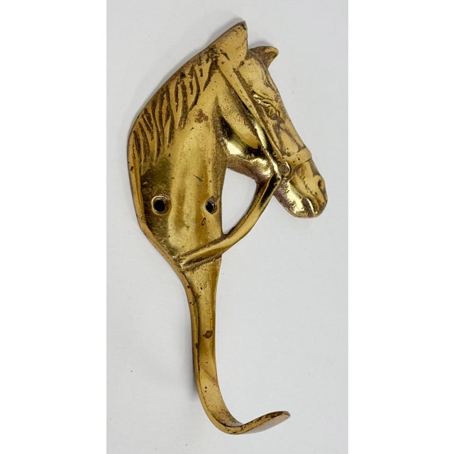Solid brass wall hook featuring horse head motif. Holes for hanging. Lovely patina.