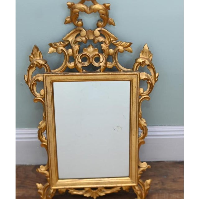 Elegant Italian Rococo style wall mirror with a richly carved giltwood frame Decorated with pierced scrolling acanthus...