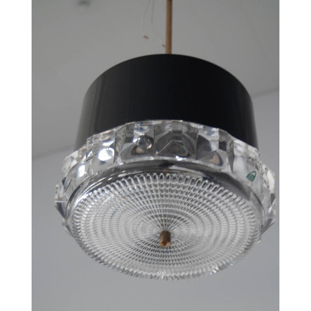 A pendant by Orrefors, Sweden, circa 1970. Dark-grey lacquered aluminum shade withe glass decoration. Marked Orrefors....