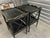 Elegant pair of Amy Howard two-tier side tables (end tables or nightstands) finished in a rich black paint with subtle...