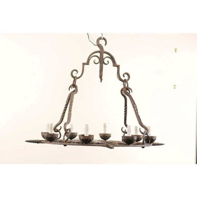 A French midcentury eight-light chandelier. This French chandelier from the mid-20th century of forged iron has a...