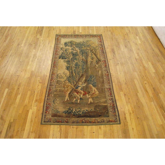 A French Aubusson rustic tapestry from the 18th century, envisioning a wooded landscape in which several youngsters play...
