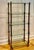 A striking mid-century brass and glass étagère featuring five substantial glass shelves suspended within a framework of...