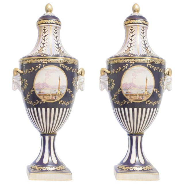 Couple of big amphoras with lids. Ceramic painted in white, blue and gold. Landscape on the front.