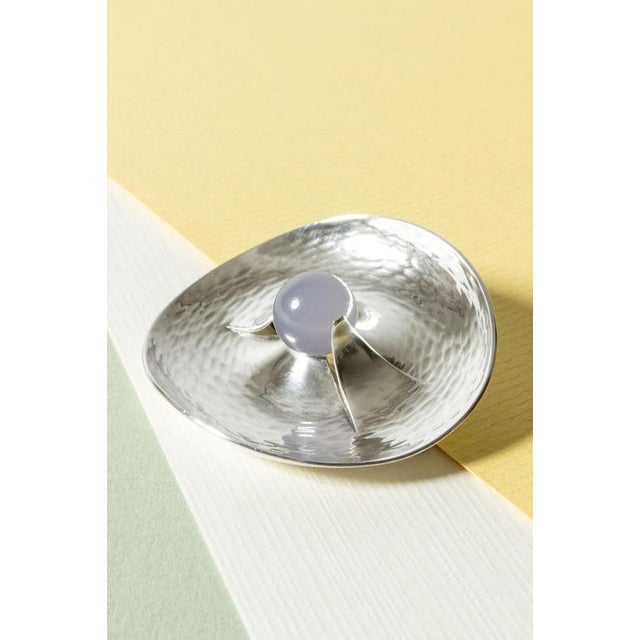 Amazing silver brooch by Elis Kauppi, in an oval form with a hammered surface that creates a rippling effect. A round...