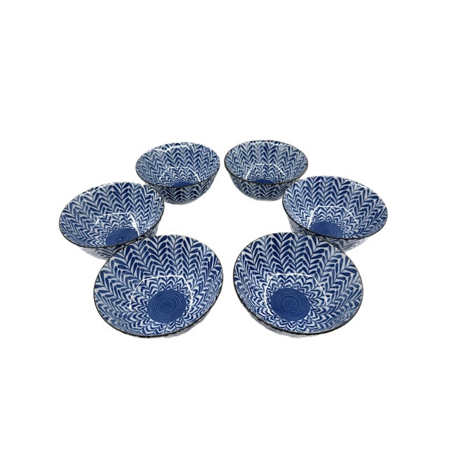 A striking set of six Japanese porcelain soup bowls featuring an all-over blue and white botanical pattern with a...