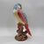 Hand-painted ceramic parrot sculpture featuring a luminous iridescent glaze and richly detailed featherwork. Perched atop...