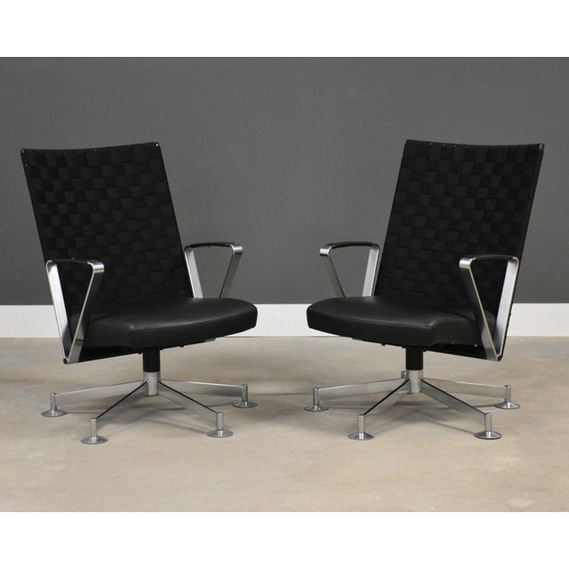 A pair of modern swivel black leather and chromed steel lounge chairs by Davis Furniture with black webbed backs and 5...