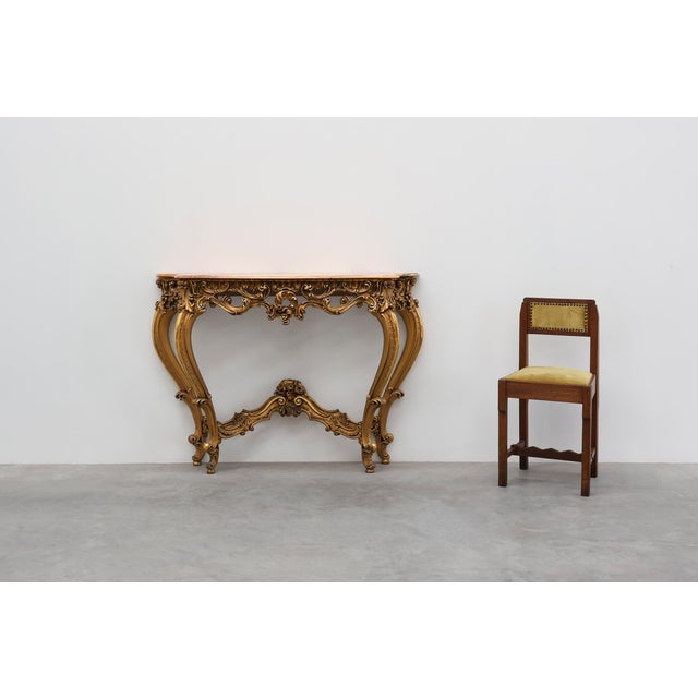 A carved Italian console table in Louis XV / Rococo Revival style, dating from the 20th century. The piece features a...