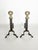 An elegant pair of fireplace andirons combining a black cast-iron structure with a polished brass decorative sphere. The...