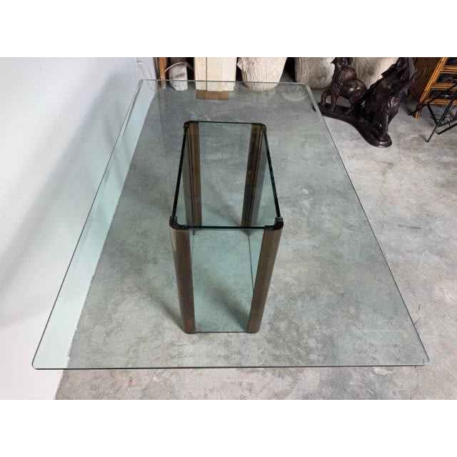 Elegant vintage dining table in the style of Pace Collection, featuring a thick, rectangular glass top with softly rounded...