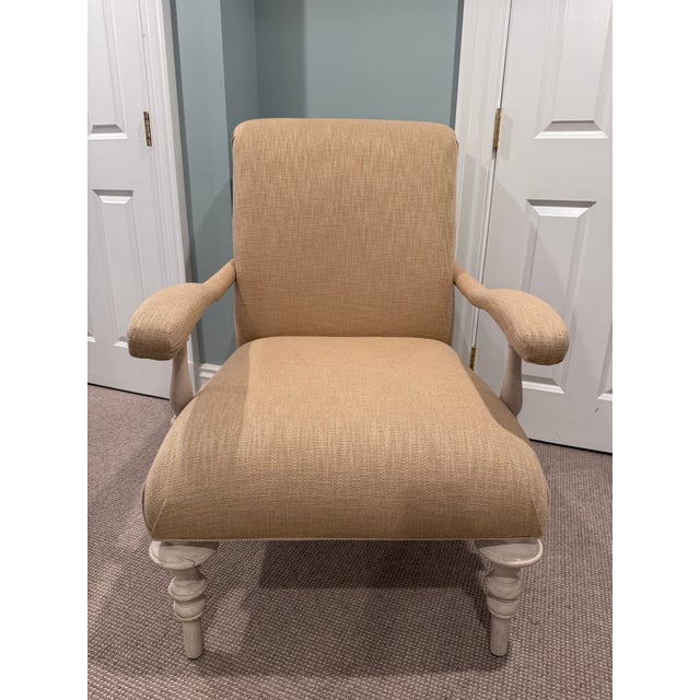Graceful and timeless accent chair featuring soft neutral beige upholstery paired with beautifully turned wooden legs in a...