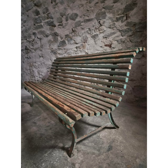 This French garden bench dates from the 1950s. It has a pair of painted iron end frames with a seat and back made from...