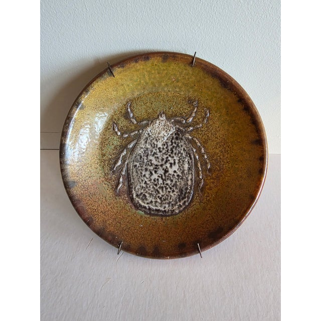 Highly unusual art pottery dish or plate with a tic on it. It is signed and dated. I can't make out the signature or the...