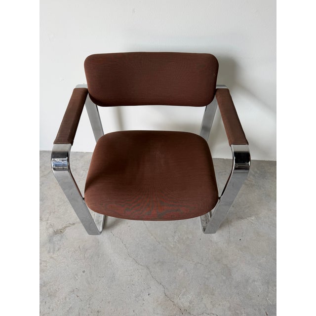 Striking vintage Italian armchair featuring a sleek chrome frame paired with warm brown fabric upholstery. The sculptural...