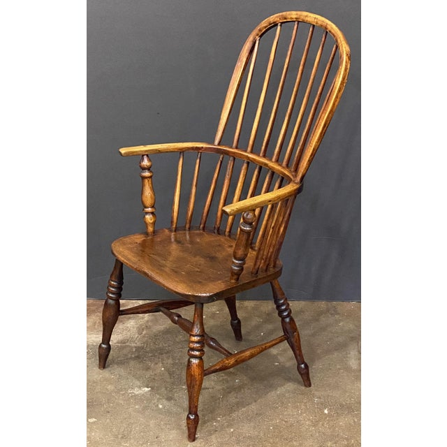 A handsome Windsor high back armchair of elm from Georgian era England, featuring a bowed top rail and spindle back, with...