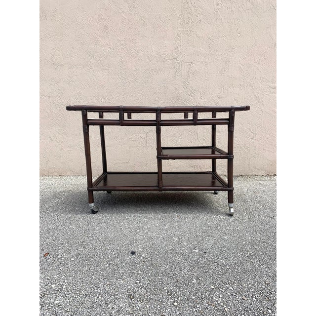 Rattan bar cart attributed design by John Wisner. Manufactured by Ficks Reed. No makers mark. Made of wood, cane and...
