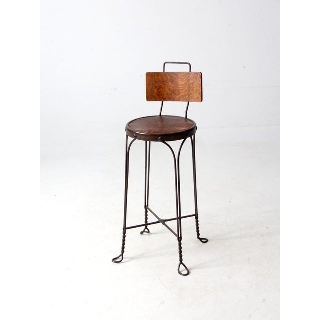 This antique stool features a twisted wire frame in the classic ice cream parlor style. It has a round wood veneer seat...
