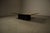 The table features a rectangular wooden top clad with an etched brass plate, resting on a black lacquered metal base with...