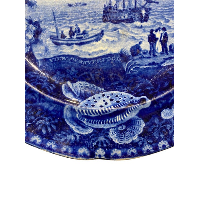 Flow blue transfer decorated plate, Enoch Wood & Son, circa 1820-30. Nautical scene with seashell border titled "View of...