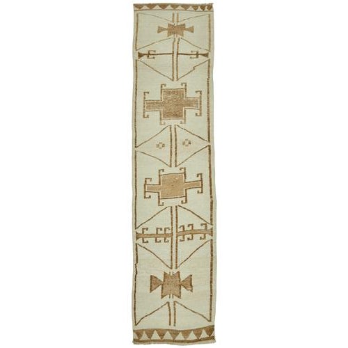 This exquisite runner rug is a rare example of tribal craftsmanship, hand-knotted by the women of the Herki tribe during...