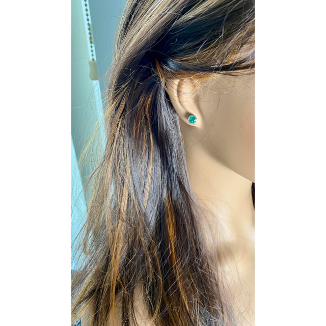 Discover the elegance and sophistication of our 14 Karat White Gold Bezel-Set Round Emerald Stud Earrings. These stunning...