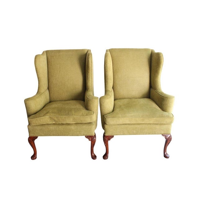 A classic and comfortable pair of vintage Queen Anne–style wingback chairs, upholstered in an olive green soft chenille...