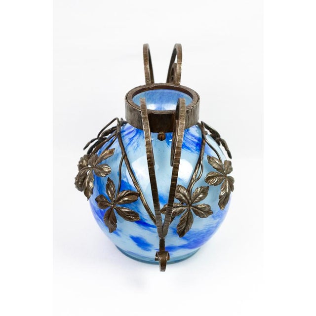Free-blown marbled glass, colored by surface vitrification: the cobalt blue diffuses in irregular patches on a milky white...