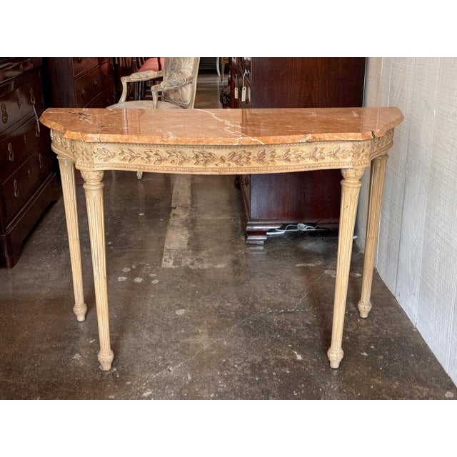 Mid 20th century Italian Louis XVI style console with a shaped top of rosy salmon marble with white veining, over a...