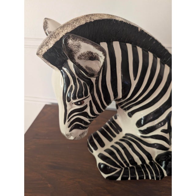 Striking vintage zebra sculpture featuring a bold black and white pattern and a sculptural, resting pose. This eye-...