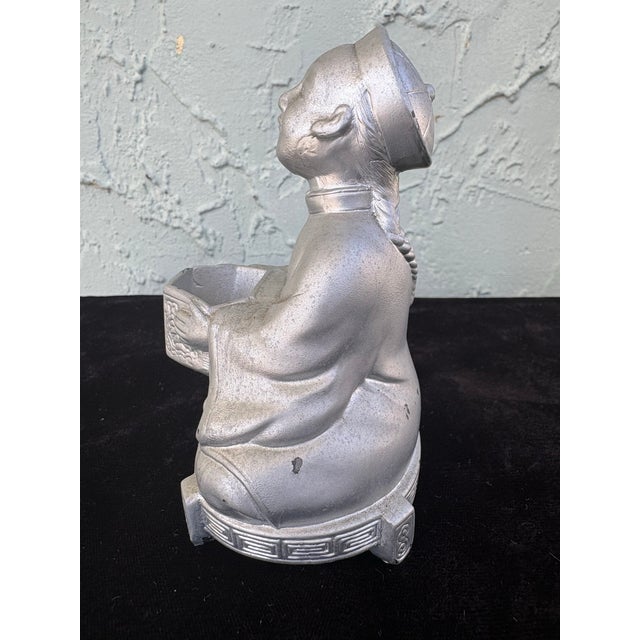 This vintage Asian figural incense burner depicts a seated scholar figure dressed in traditional robes and holding a small...