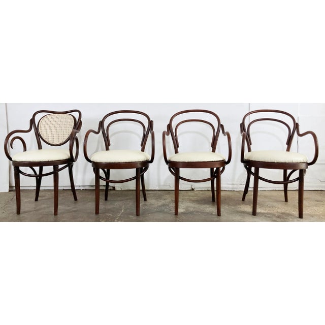 Set of four antique bentwood dining chairs, each featuring rolled bentwood arms and rich natural wood stain. Three chairs...