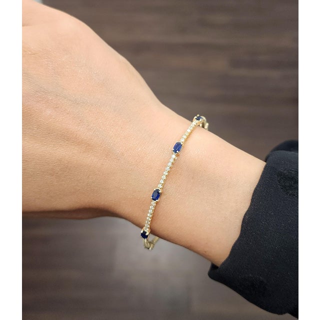 This exquisite bangle bracelet captivates with its modern allure. Adorned with 7 natural striking blue oval sapphires,...