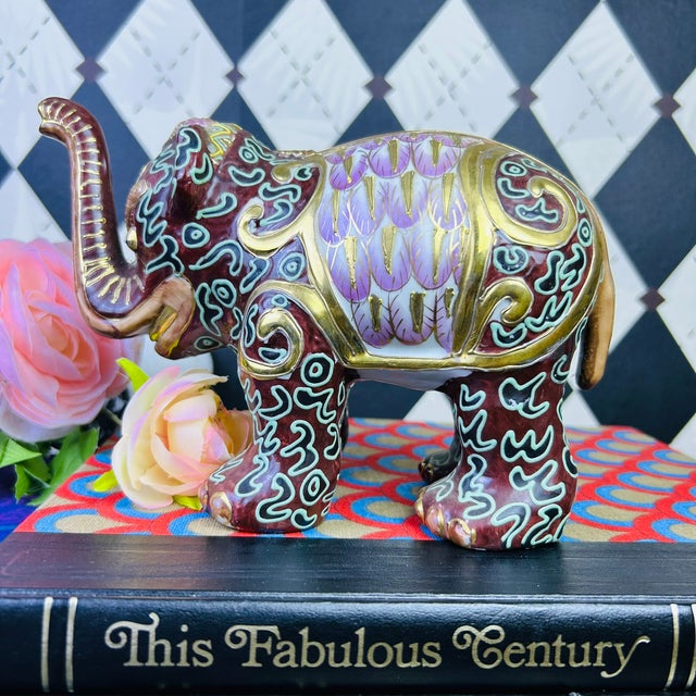 Pair of decorative ceramic elephant figurines featuring a rich burgundy glaze accented with blush pink, lavender,...